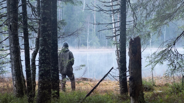 Man standing near a lake in the forests in the autumn