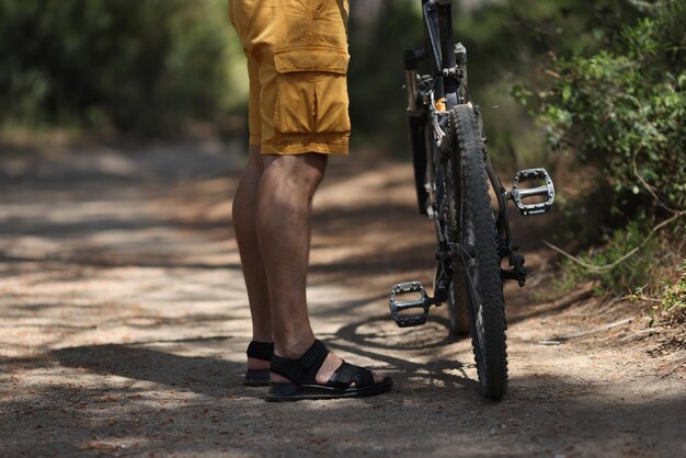 Photo man standing near mountain bike on path in forest closeup