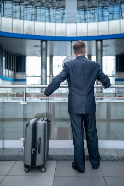 Man standing near suitcase with back to camera