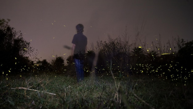 写真 夜空に逆らって野原に立っている男