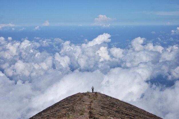 写真 天に向かって山の上に立っている男