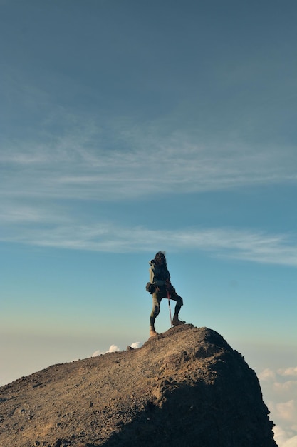 写真 天に向かって岩の上に立っている男