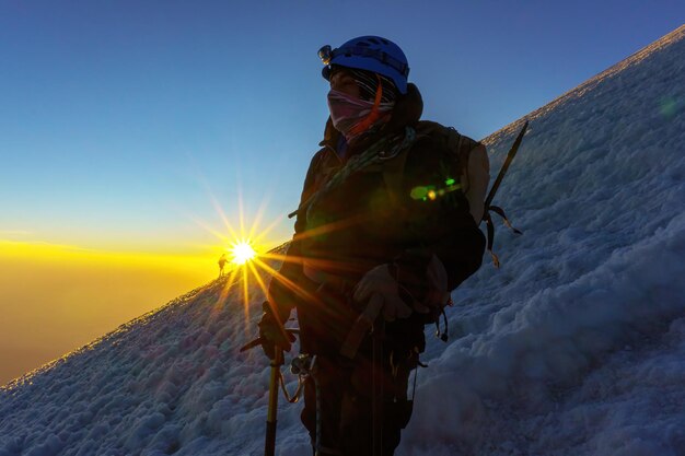 写真 夕暮れの間に雪で覆われた山の上に立っている男