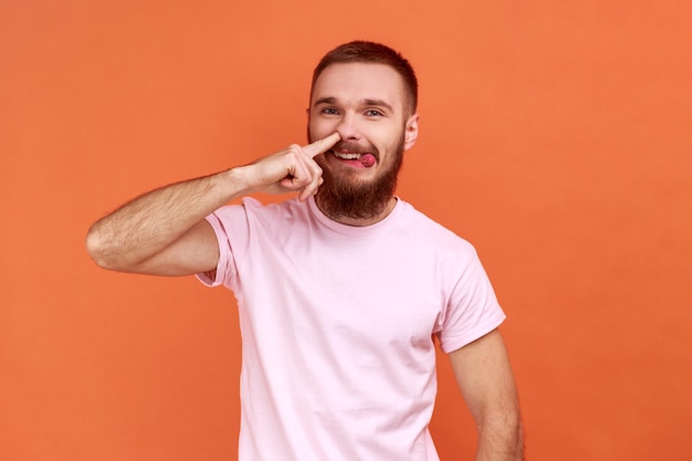 Man standing picking nose and sticking out tongue with dumb comical expression fooling around