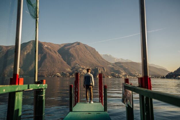 スイスのルガーノ湖の桟橋に立っている男。