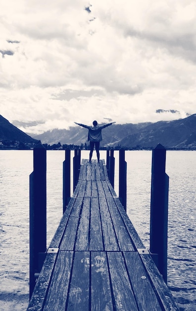 Photo man standing on pier over sea against sky