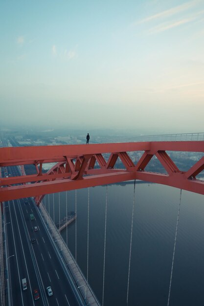 Photo man standing on railing over river against sky