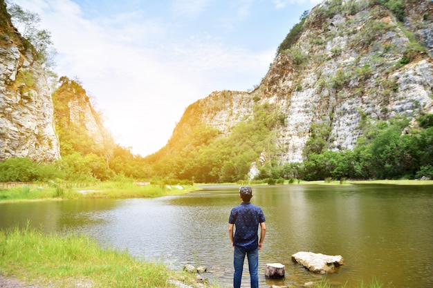 Man standing at river mountain background nature sunlight