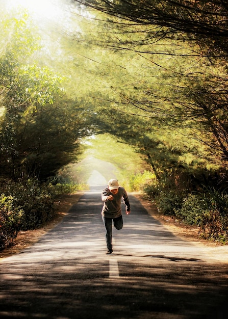 Photo man standing on road amidst trees