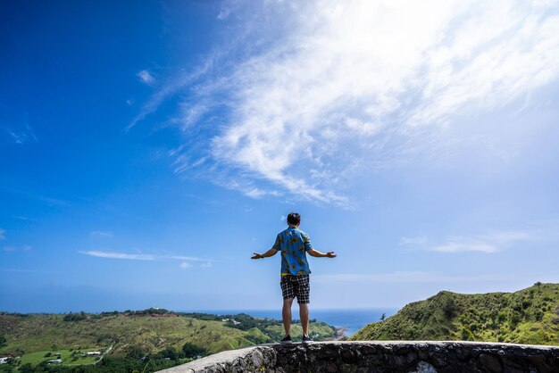 Man standing on rock against blue sky