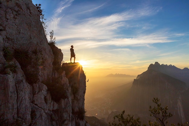 Man standing on rock against sky during sunset