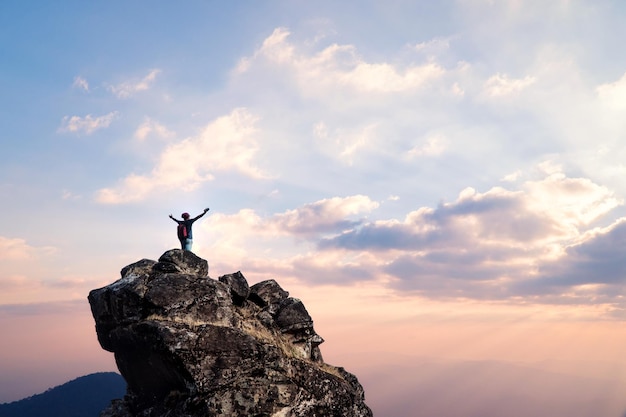 Man standing on rock against sky at sunset