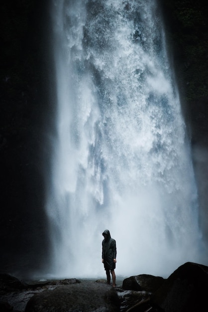 Photo man standing on rock against waterfall