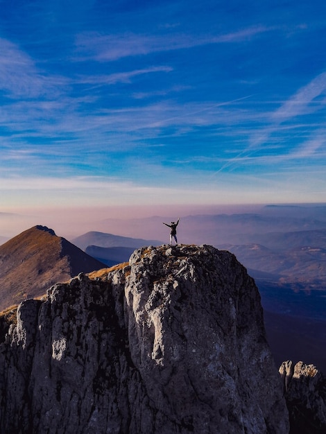 Foto uomo in piedi sulla roccia dalla montagna contro il cielo