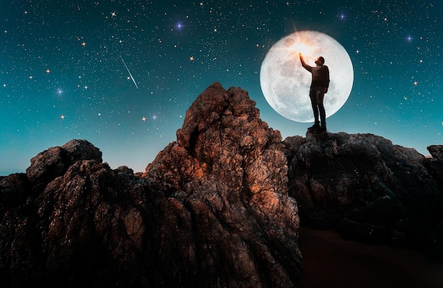 Man standing on the rock outdoors contemplating the starry night and full Moonx9