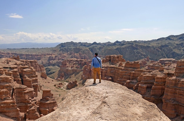 Photo man standing on a rock overlooking the magnificent screens of charyn canyon kazakhstan