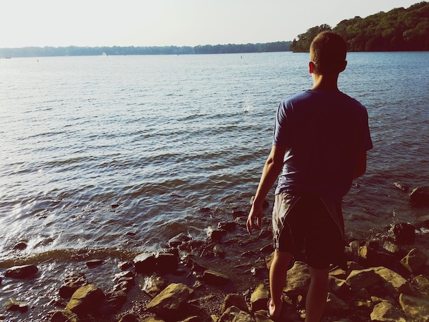 Man standing on rock at riverbank