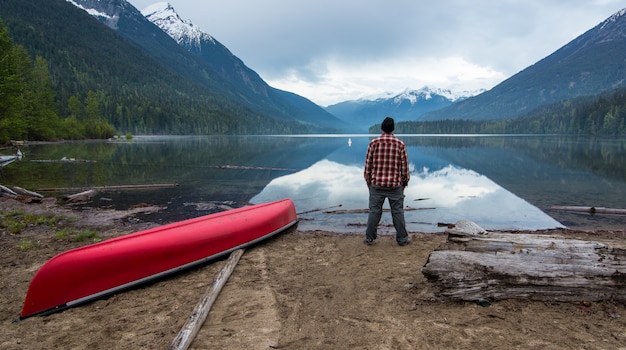 Photo man standing on short looking at a lake