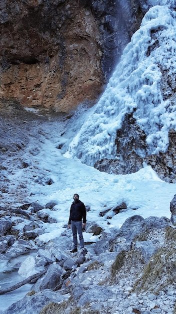 Foto uomo in piedi sulla montagna innevata