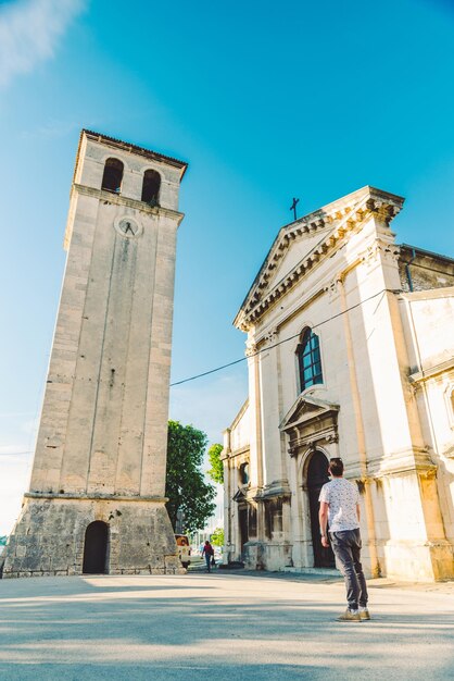 Man standing at square looking at old roman cathedral church in pula city