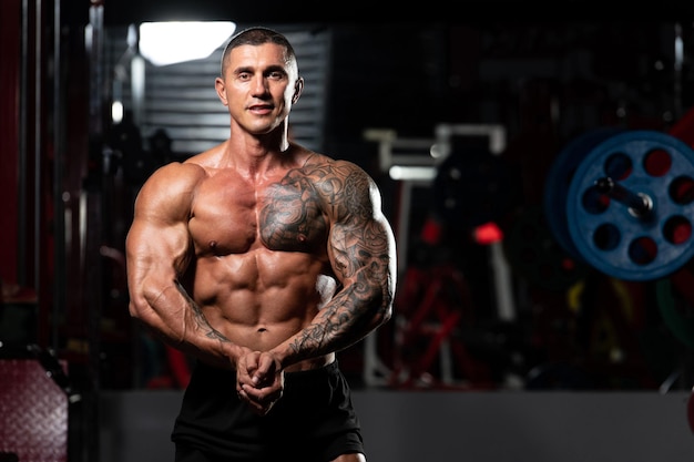 Man Standing Strong In The Gym And Flexing Muscles Muscular Athletic Bodybuilder Fitness Model Posing After Exercises