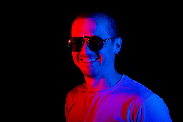 Man standing in studio under red and blue color lights at black background