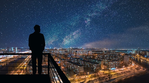 L'uomo in piedi in cima all'edificio sullo sfondo stellato del paesaggio urbano