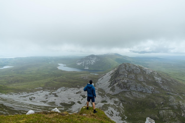 Errigal 山株式会社ドニゴール アイルランドの風景を眺めながら山の頂上に立っている男