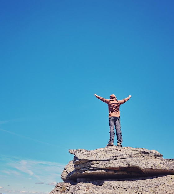 Man standing on top of rock in the clouds background