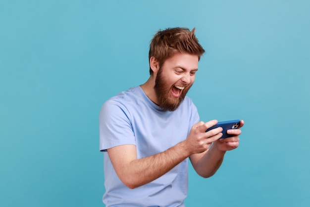 Man standing using smartphone and playing mobile game with excited positive face happy to win