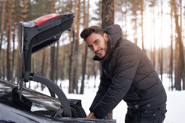 車の近くの冬の森に立っている男