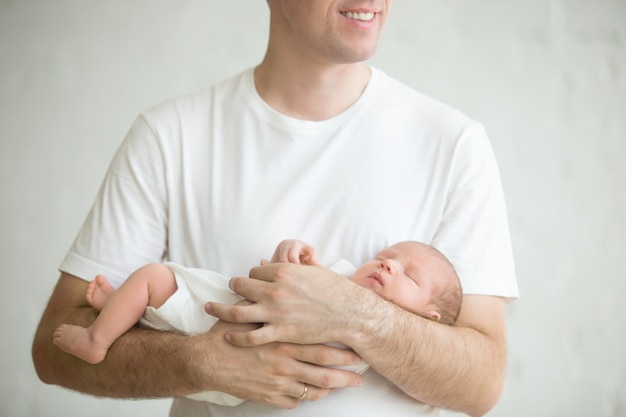 사진 팔에 잠자는 아기와 함께 서있는 남자