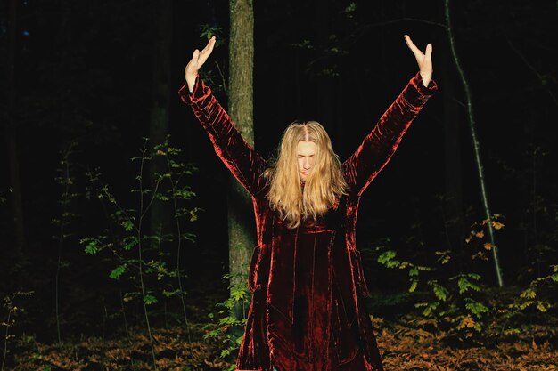 Photo man standing with arms outstretched against trees in forest at night