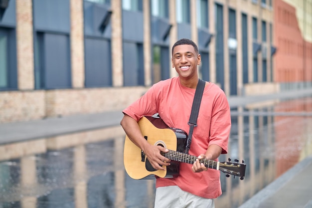 Man standing with guitar smiling at camera