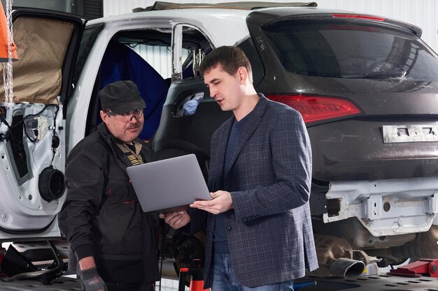 Photo man standing with mechanic in garage