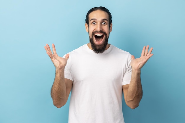 Man standing with mouth open in surprise has shocked expression keeping hands raised