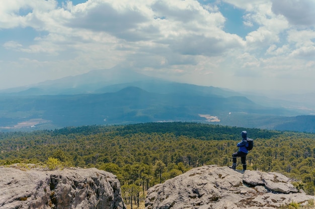 A man stands alone on the peak of rock