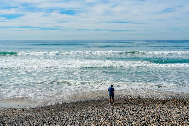 A man stands on a beach in front of the ocean.