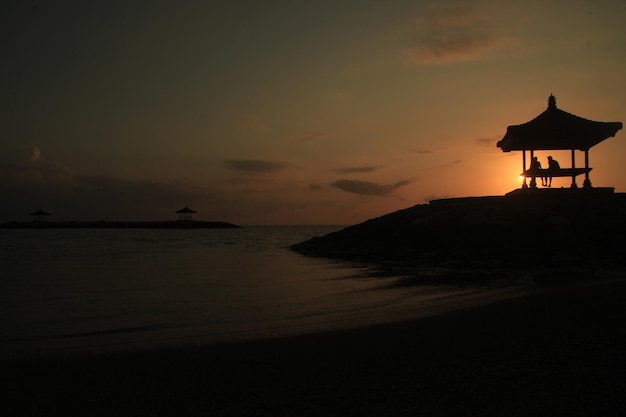 A man stands on a beach with a boat in the background.