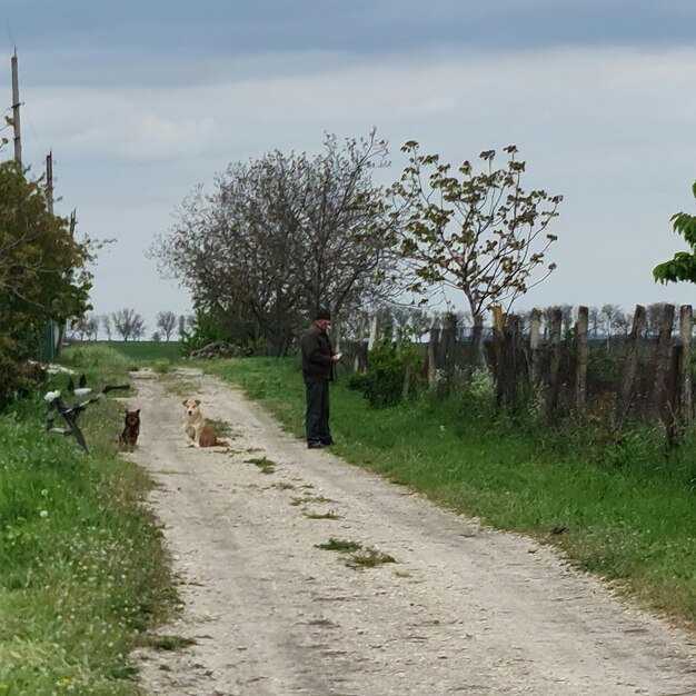 男が犬を連れて未舗装の道路に立っています。