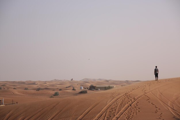 A man stands on a dune in the desert