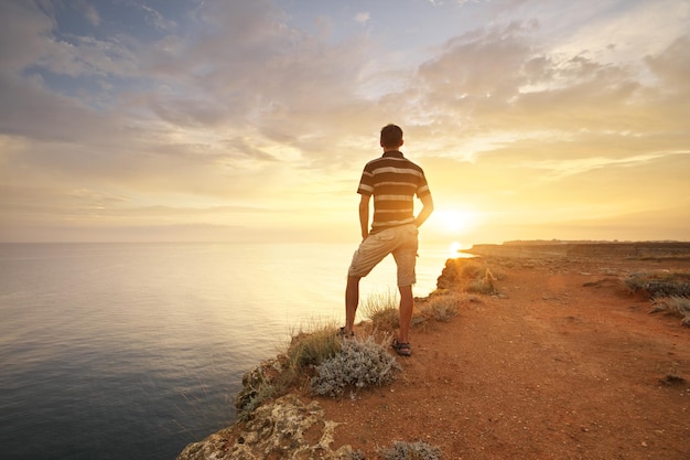 Foto l'uomo sta sull'orlo dell'abisso e guarda il mare