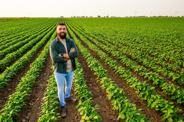 A man stands in a field of soybeans which is green and has a green jacket on