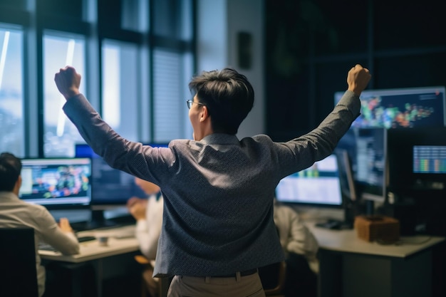 A man stands in front of a computer screen with his arms raised in the air.