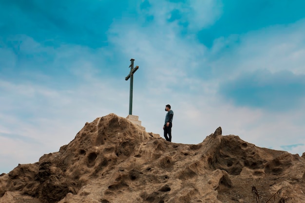 남자는 산에 십자가 앞에 서 있다