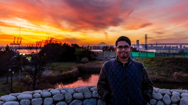 A man stands in front of a sunset