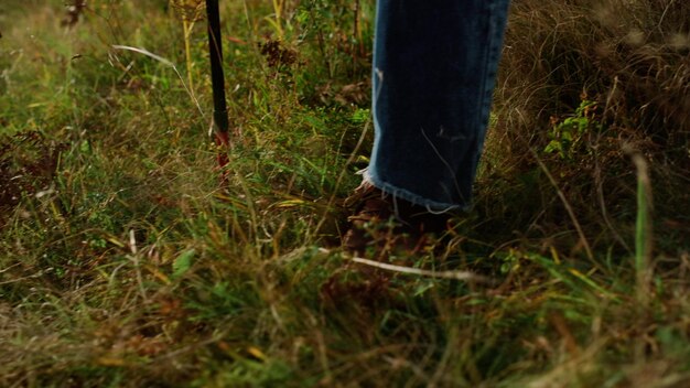 A man stands in the grass with a stick in his hand