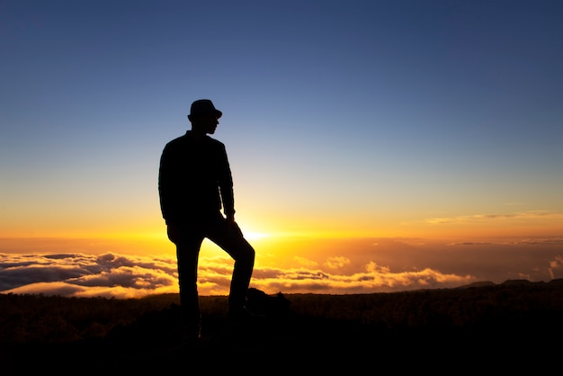 Man stands on a mountain at sunset 