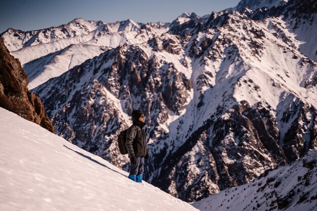 A man stands on a mountainside and looks into the distance