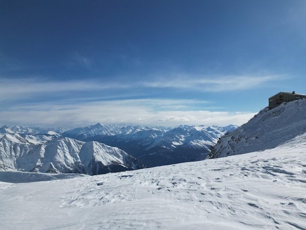 A man stands on a snowy mountain with a mountain in the background